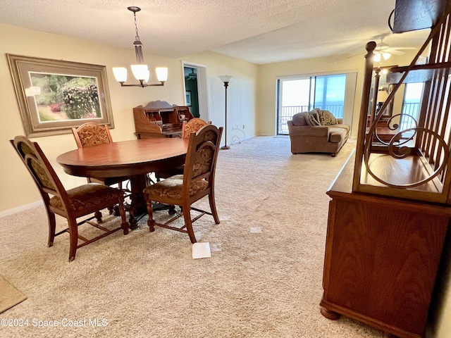 carpeted dining room with a textured ceiling and ceiling fan with notable chandelier