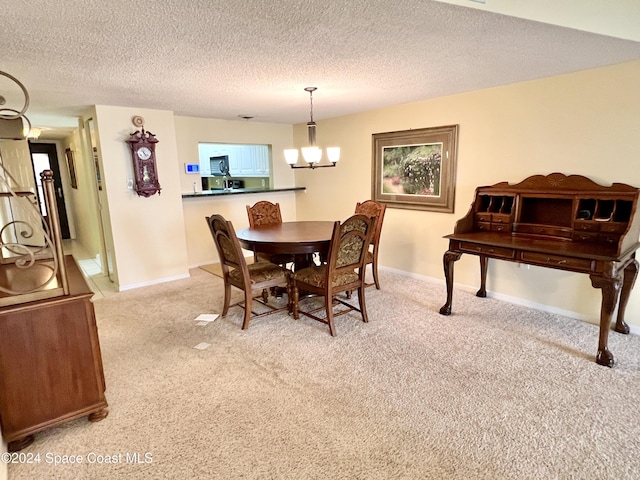 carpeted dining space with a notable chandelier and a textured ceiling