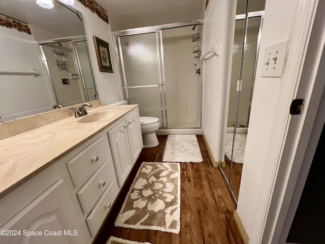 bathroom with walk in shower, hardwood / wood-style floors, vanity, and toilet