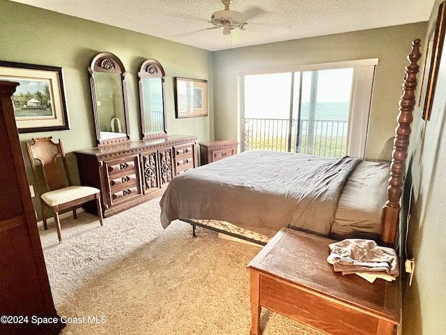 bedroom featuring carpet flooring, ceiling fan, a water view, and a textured ceiling