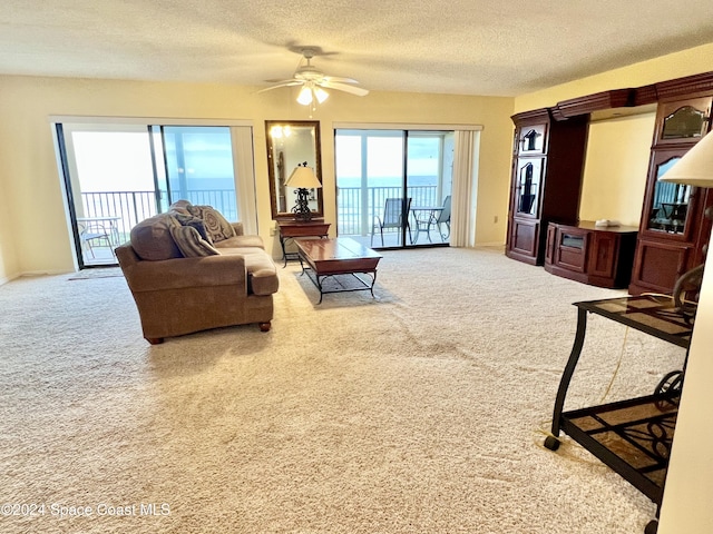 living room with carpet flooring, ceiling fan, and a textured ceiling