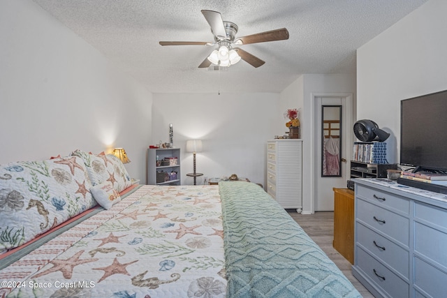 bedroom with ceiling fan, light hardwood / wood-style flooring, and a textured ceiling