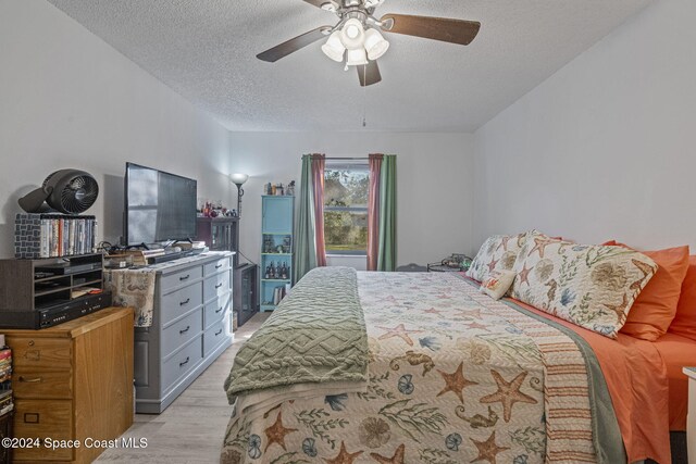 bedroom featuring ceiling fan, a textured ceiling, and light wood-type flooring