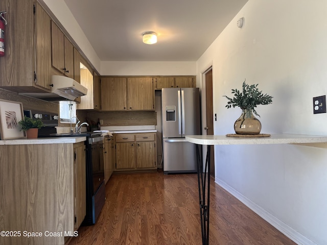 kitchen featuring tasteful backsplash, kitchen peninsula, appliances with stainless steel finishes, and dark hardwood / wood-style flooring