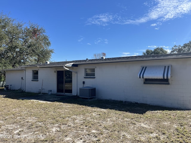 rear view of property with a lawn and central air condition unit