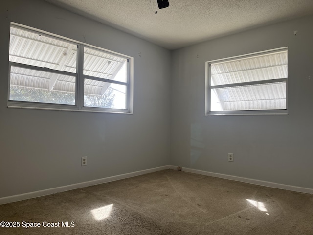 carpeted spare room featuring ceiling fan and a textured ceiling