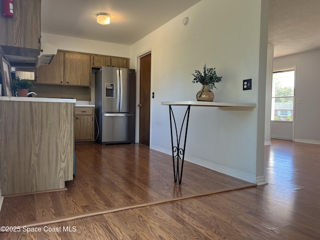 kitchen featuring backsplash, dark hardwood / wood-style flooring, stainless steel fridge with ice dispenser, and a textured ceiling