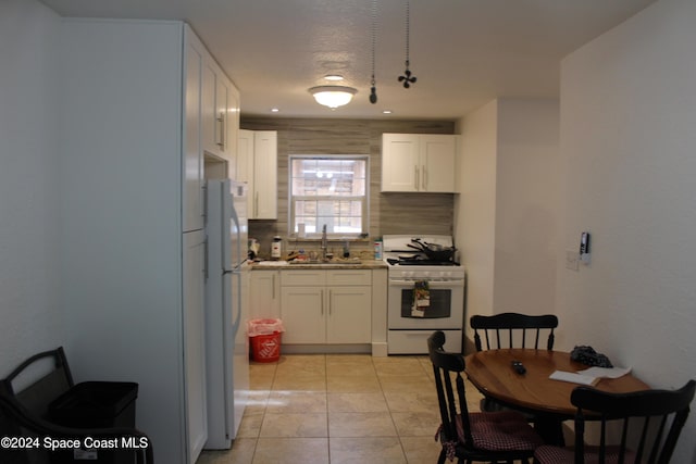 kitchen featuring decorative backsplash, white appliances, sink, white cabinetry, and light tile patterned flooring