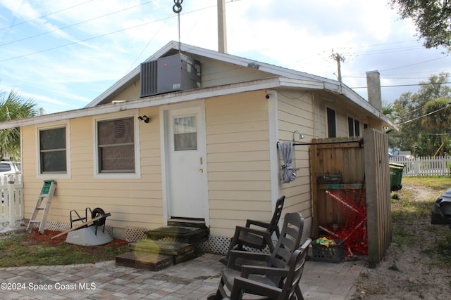 rear view of property with central AC unit and a patio