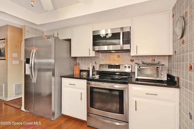 kitchen featuring stainless steel appliances, light hardwood / wood-style flooring, and white cabinetry