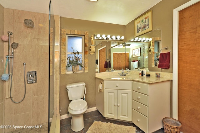 bathroom featuring tile patterned floors, vanity, a tile shower, and toilet