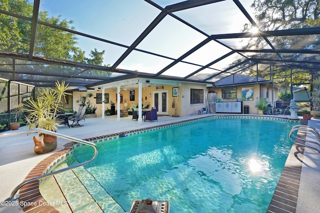 view of swimming pool featuring ceiling fan, glass enclosure, french doors, and a patio