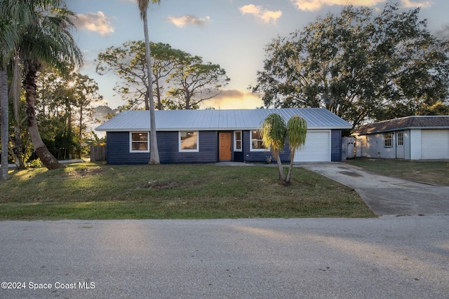 ranch-style house with a garage and a yard