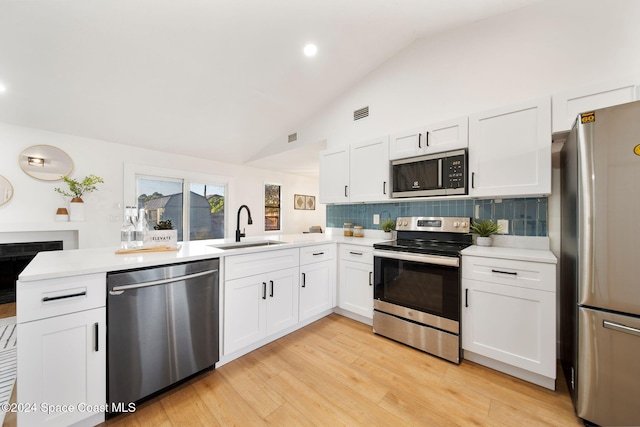 kitchen with sink, stainless steel appliances, kitchen peninsula, light hardwood / wood-style floors, and white cabinets