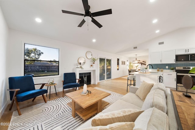 living room with a healthy amount of sunlight, vaulted ceiling, and light wood-type flooring