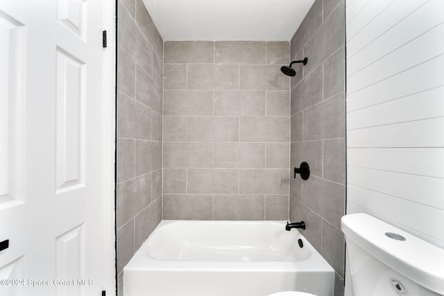 bathroom with toilet and tiled shower / bath