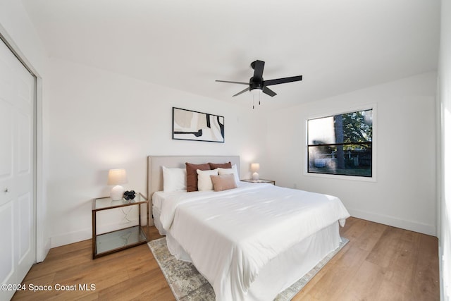 bedroom with ceiling fan, light hardwood / wood-style flooring, and a closet