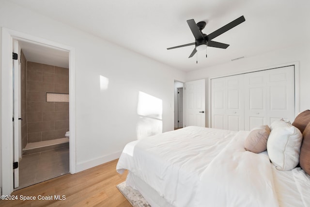 bedroom featuring a closet, light hardwood / wood-style floors, ensuite bath, and ceiling fan