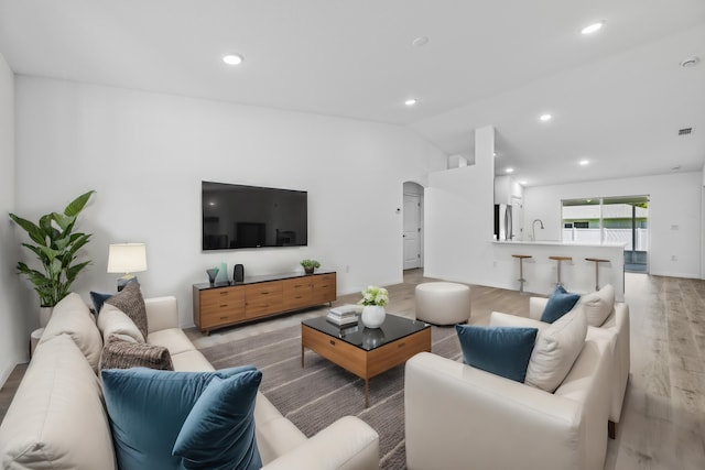 living room featuring light hardwood / wood-style floors, lofted ceiling, and sink