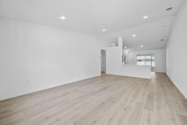 unfurnished living room featuring light hardwood / wood-style flooring, lofted ceiling, and sink