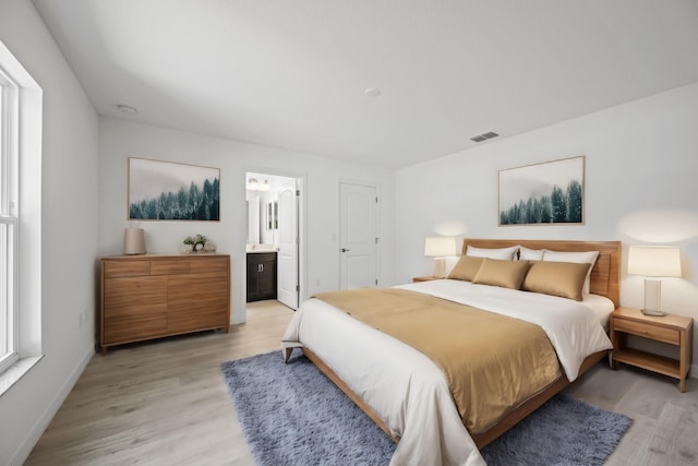 bedroom featuring ensuite bathroom and light hardwood / wood-style flooring