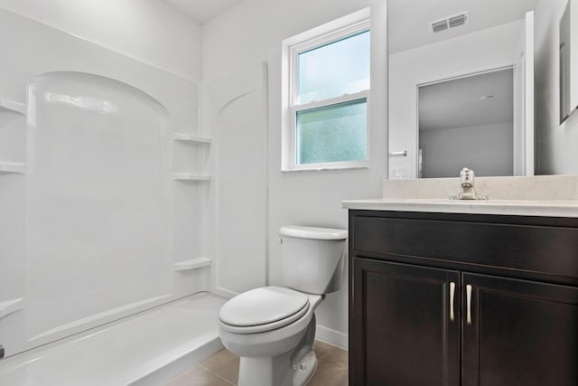 bathroom featuring tile patterned flooring, vanity, toilet, and walk in shower