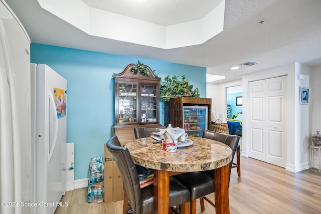 dining room featuring light wood-type flooring and a textured ceiling