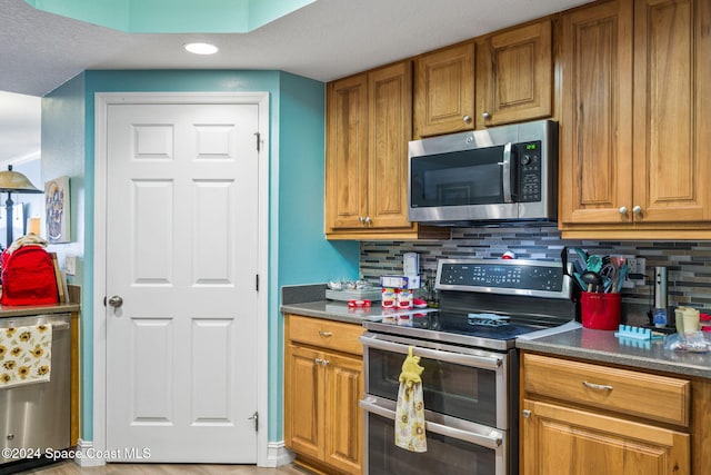 kitchen with tasteful backsplash, stainless steel appliances, a textured ceiling, and hardwood / wood-style flooring