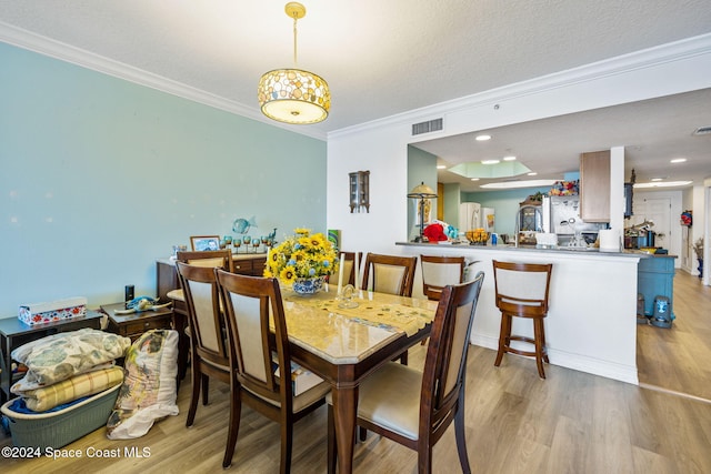 dining area with a textured ceiling, light hardwood / wood-style floors, and crown molding