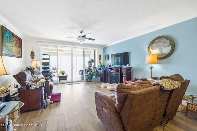 living room featuring a textured ceiling, light hardwood / wood-style floors, ceiling fan, and crown molding