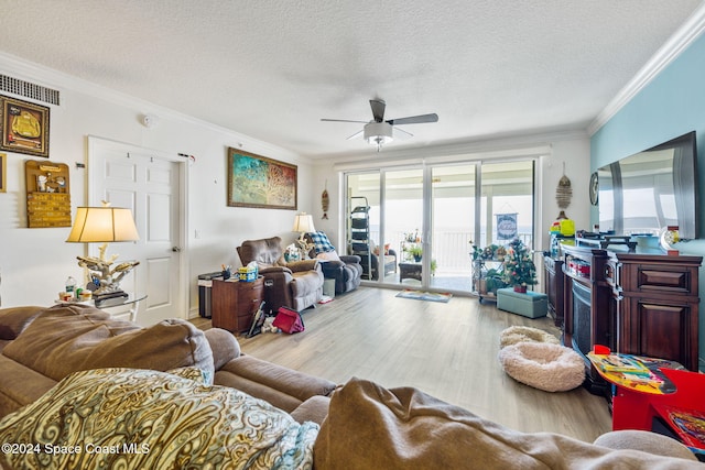 living room with ceiling fan, hardwood / wood-style floors, a textured ceiling, and ornamental molding