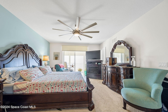 bedroom featuring light carpet, a textured ceiling, and ceiling fan