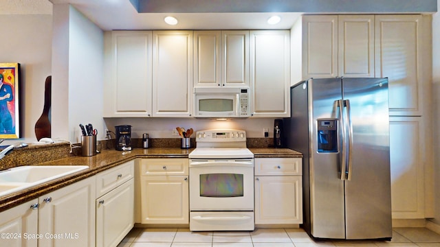 kitchen featuring white cabinets, light tile patterned floors, and white appliances