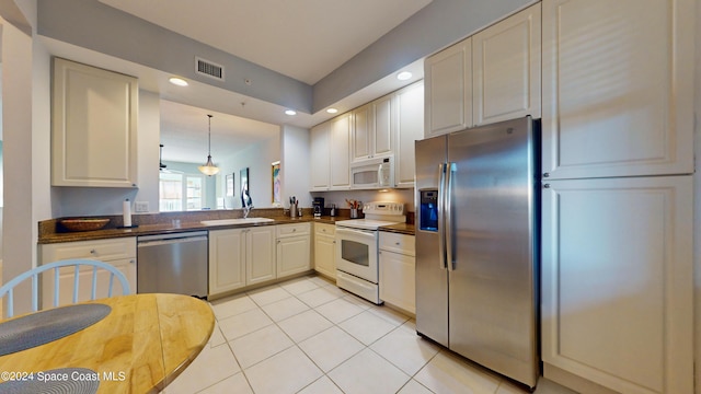 kitchen with appliances with stainless steel finishes, sink, decorative light fixtures, and light tile patterned flooring