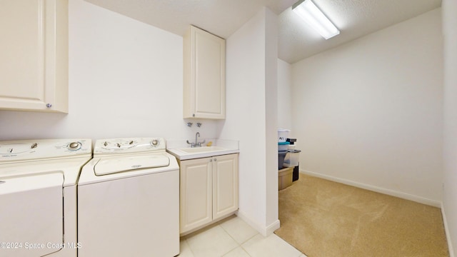 laundry room with sink, cabinets, separate washer and dryer, light colored carpet, and a textured ceiling