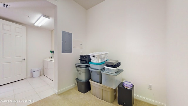 clothes washing area with washer and clothes dryer, light carpet, and electric panel