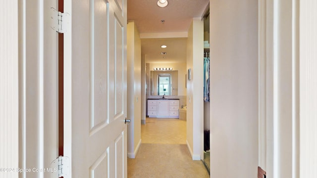 hallway featuring a textured ceiling, light colored carpet, and sink