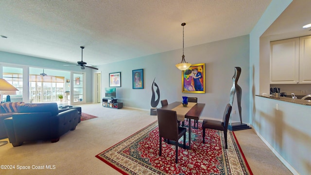 dining room featuring ceiling fan, light colored carpet, and a textured ceiling