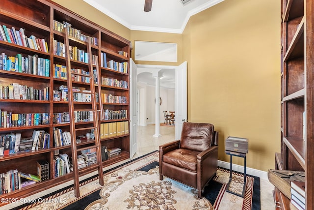 sitting room with ornate columns, crown molding, and ceiling fan