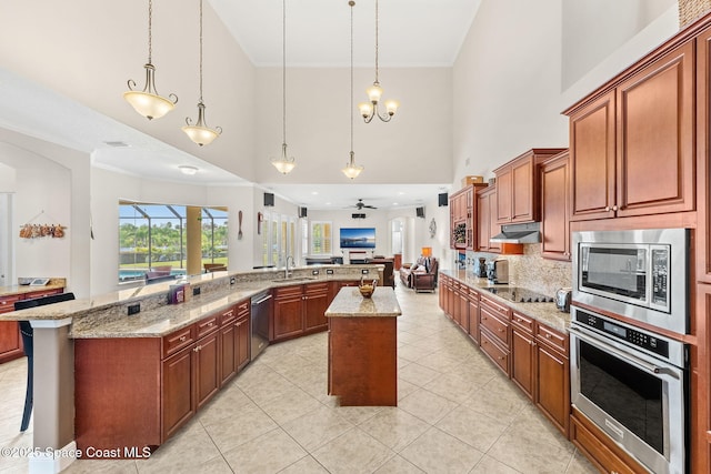 kitchen featuring a large island, sink, appliances with stainless steel finishes, a kitchen bar, and decorative light fixtures