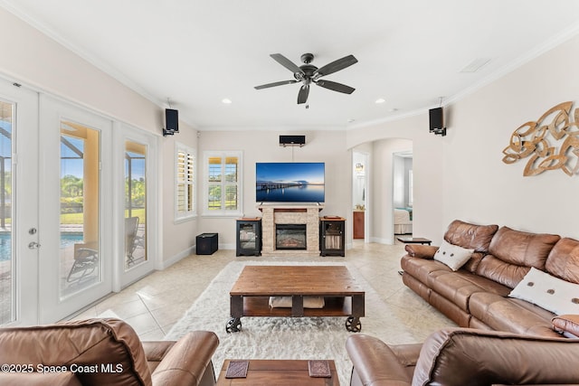 living room with light tile patterned floors, crown molding, a fireplace, and ceiling fan