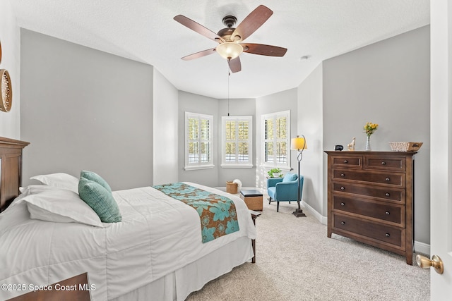 bedroom featuring ceiling fan, light carpet, and a textured ceiling