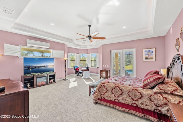 bedroom with an AC wall unit, a raised ceiling, carpet floors, ceiling fan, and access to exterior