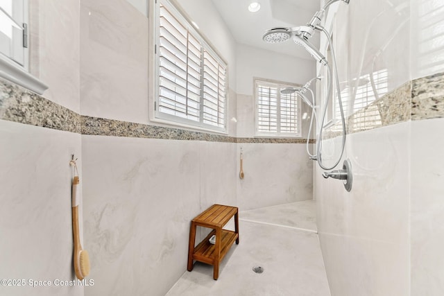 bathroom featuring walk in shower and tile walls