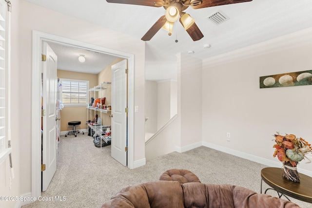 interior space featuring ceiling fan, light colored carpet, and a textured ceiling