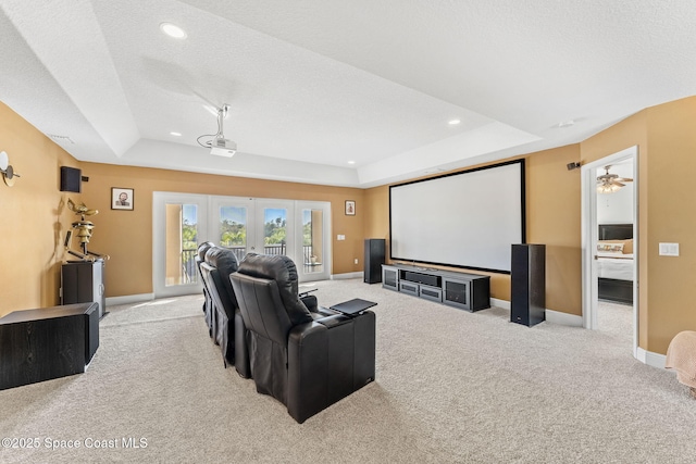 carpeted home theater featuring a tray ceiling, french doors, and a textured ceiling