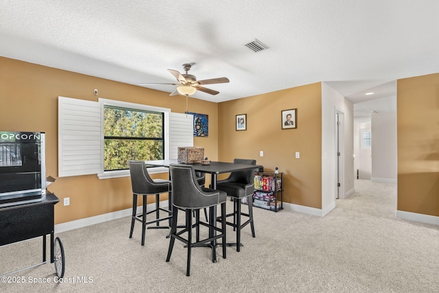 carpeted dining space featuring ceiling fan and a textured ceiling