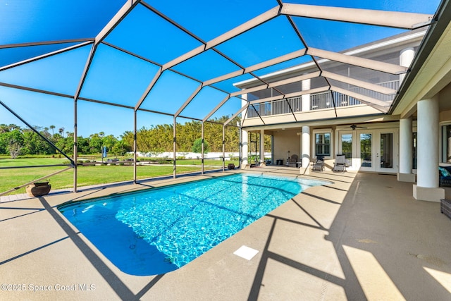 view of pool featuring a lawn, ceiling fan, glass enclosure, a patio area, and french doors