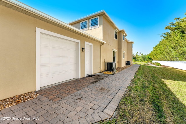 view of home's exterior with a garage, central AC unit, and a lawn