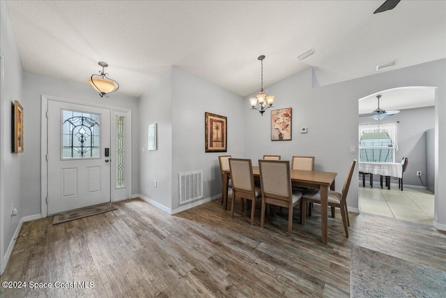 dining room with hardwood / wood-style flooring, lofted ceiling, and ceiling fan with notable chandelier